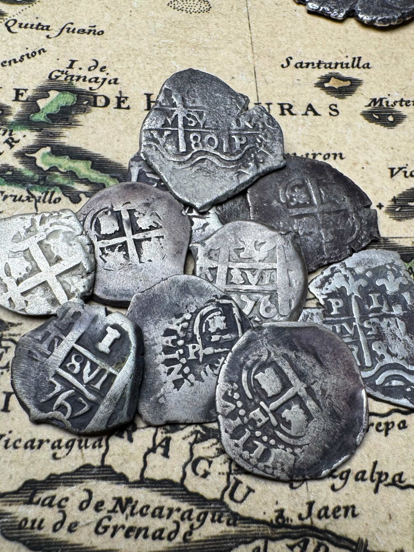 Pile of worn Spanish colonial 1 reale cobs with visible dates and mint marks