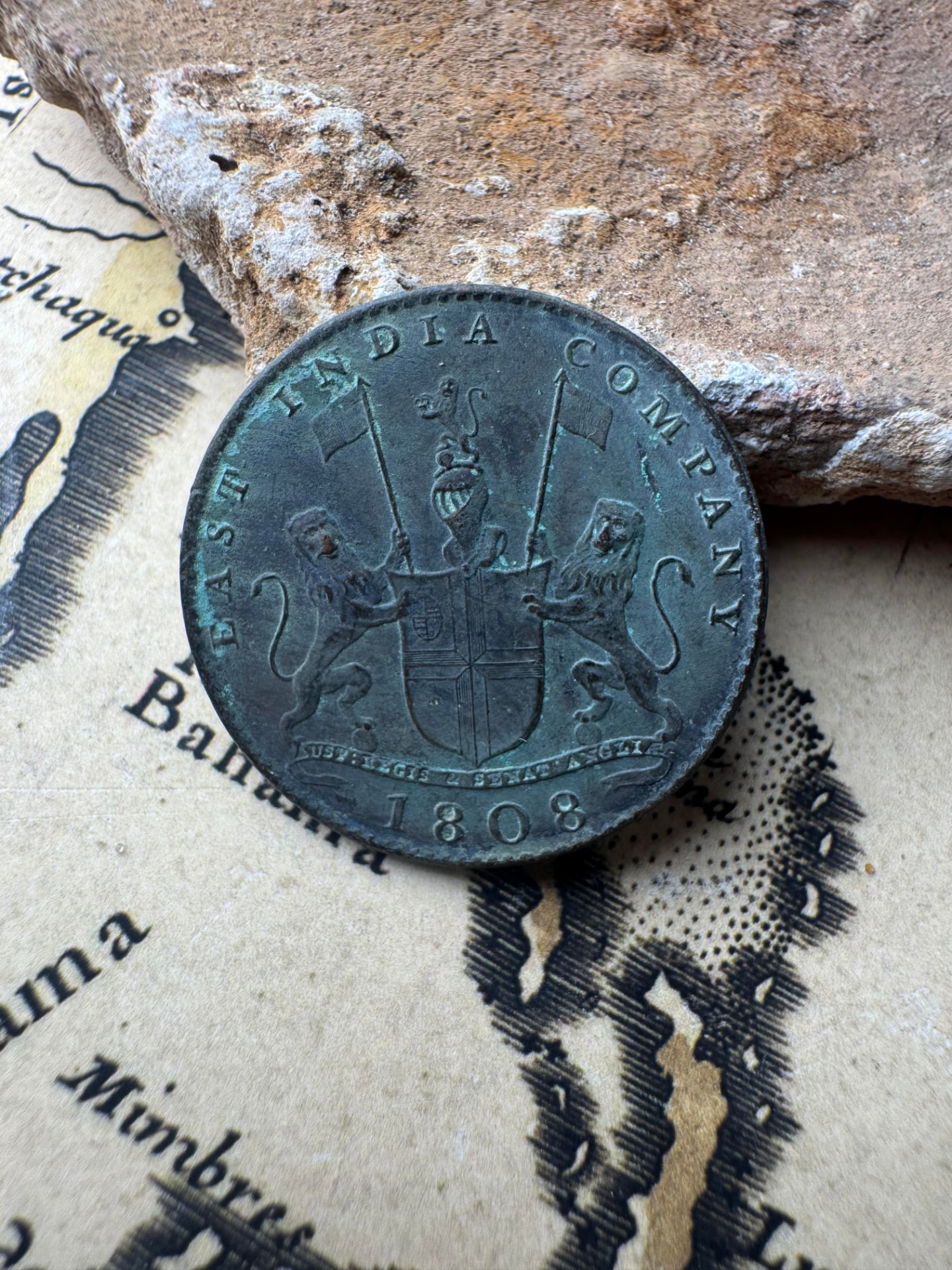 1808 East India Company coin showing the company arms, on an antique chart