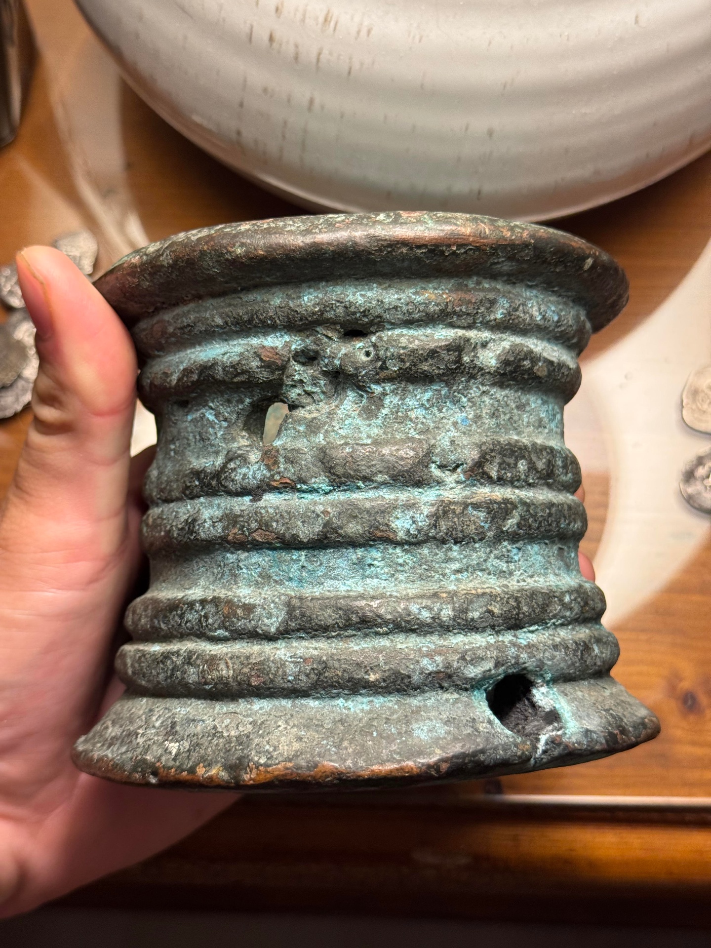 Side view of a ribbed bronze thunder mug with green oxidation